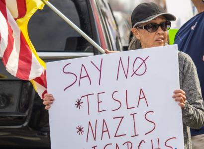 Woman holding sign at Tesla protest