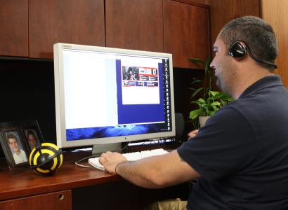 Man sitting at desk with headphones working on a computer