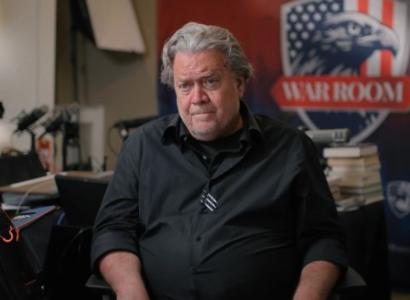 Gray haired white man by a sign reading War Room