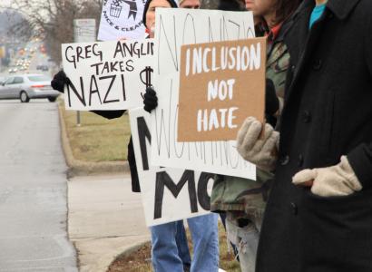 People outside holding signs that say Inclusion Not Hate and Greg Anglin takes Nazi Money