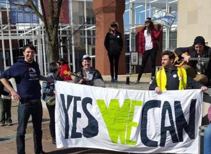 People holding a Yes We Can sign outside a brick building
