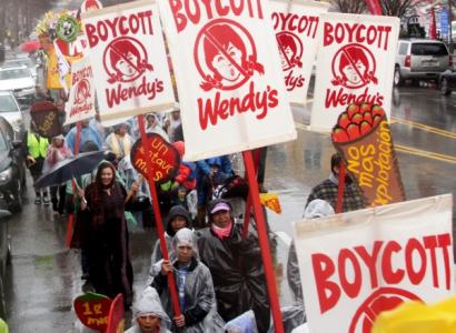 People marching in the rain with Boycott Wendy's signs