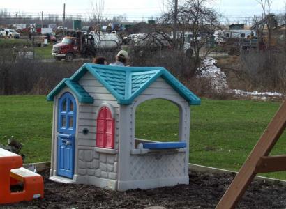 Backyard kid's playhouse with frackers working jsut behind it