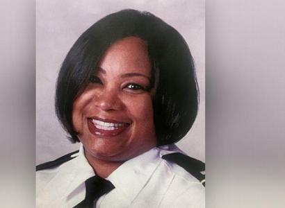 Head shot of black woman with short black hair smiling wearing a police uniform
