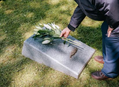 Person putting flowers on a gravestone