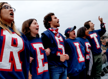 People dressed in red, white and blue with RESIST spelled out on each shirt yelliing