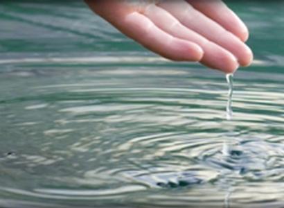 Person's hand above water with drops dripping off