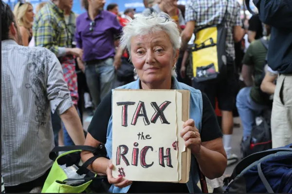 Woman holding Tax the Rich sign
