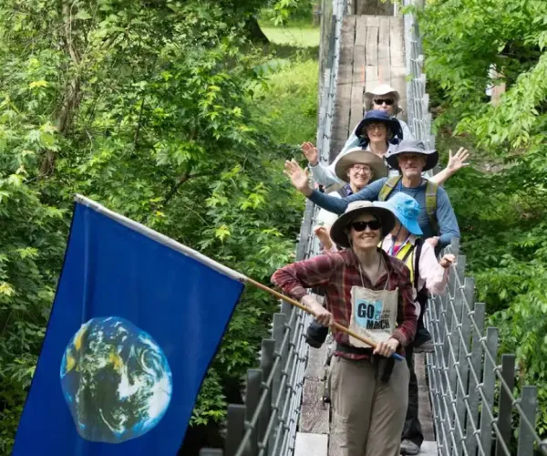Marchers posing on a bridge in the woods
