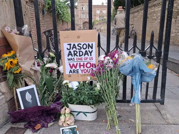 Memorials with flowers and a sign about Jason Arday