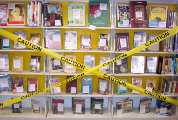 Books on shelves with Caution yellow tape across them