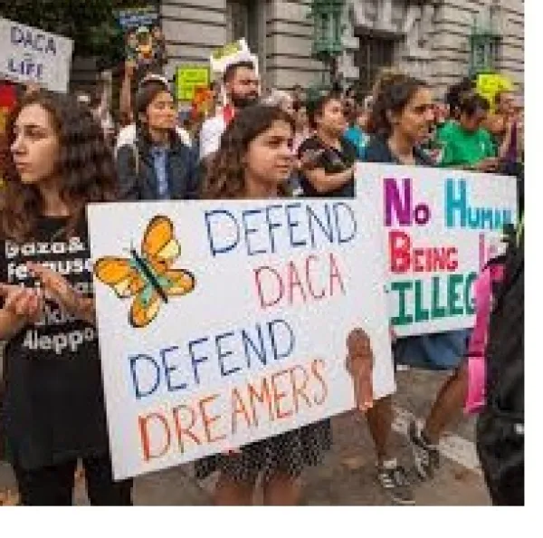 Lots of young kids holding signs outside at a demonstration that say Defend DACA Defend Dreamers and No Human Being is Illegal