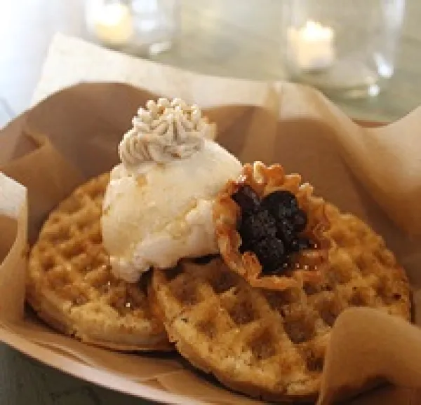 Two brown waffle-ish looking foods on a plate with a dollup of something white and something purple