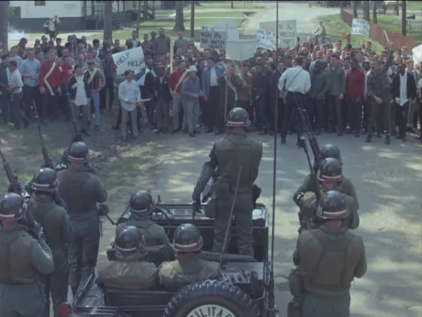 MIlitary looking men facing off a group of people