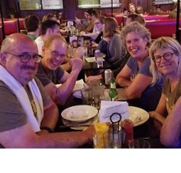 Smiling faces of white middle-aged men and women at a table in a restaurant