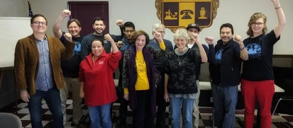 Several people smiling and standing in rows facing the camera with their fists in the air