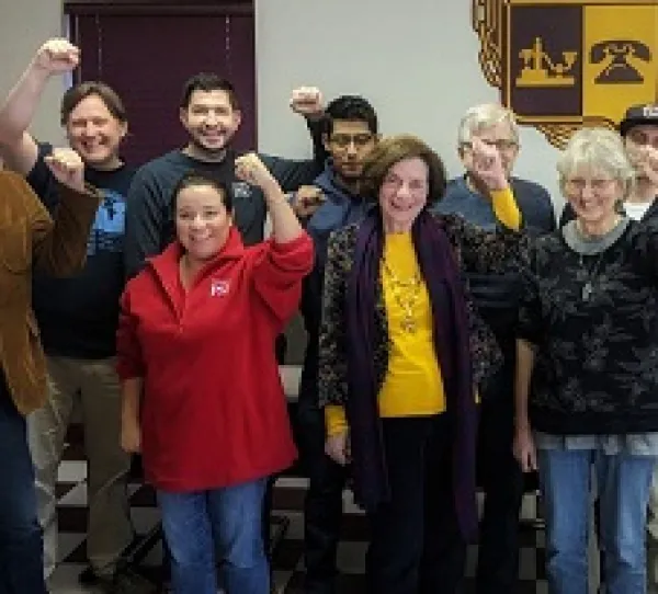 White and Latino people posing and holding their fists in the air