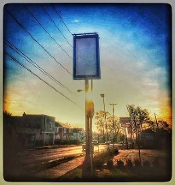 Blue background sky with a tall rectangular sign that is blank on a city street