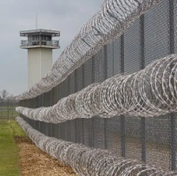 Long barbed wire fence and a tower of a prison