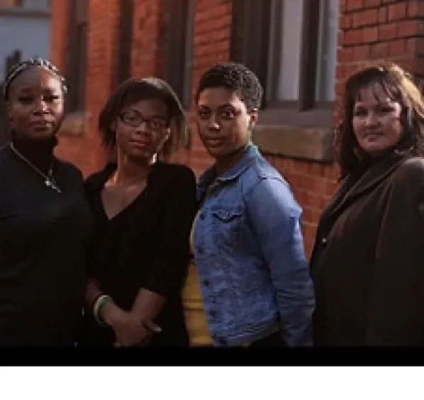 Three black women and a white woman standing outside looking very serious