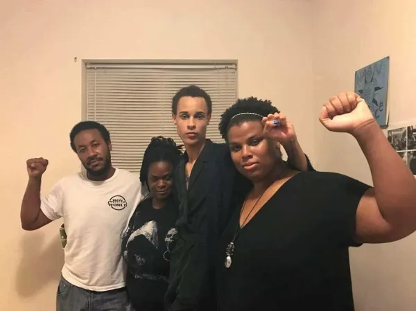 Four young black people one with fist in the air