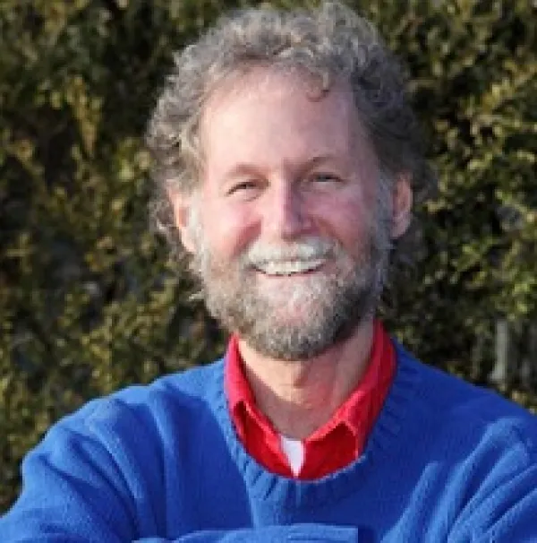 White man with curly blonde hair and a mustache and beard smiling 