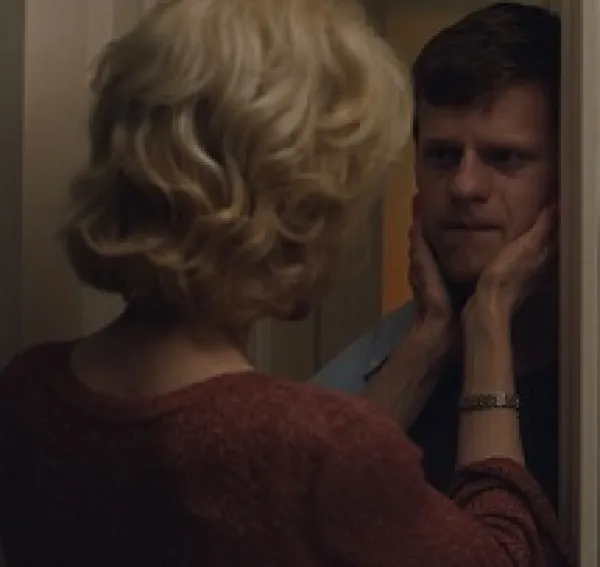 Back of wWoman with blonde buffant hairdo with both hands holding a young man's face