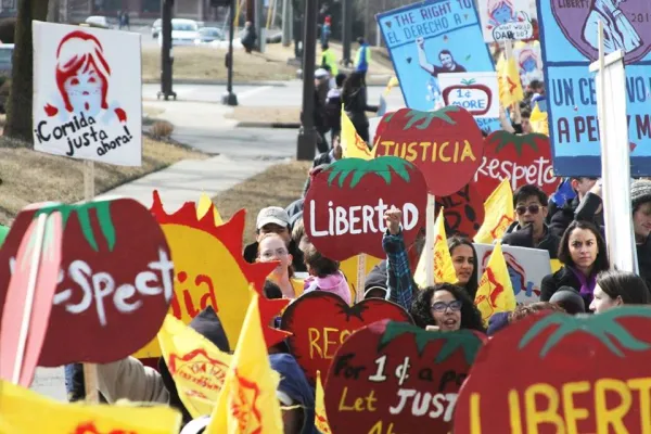 People holding bright red signs shaped like tomatoes that say Justica and Libertad
