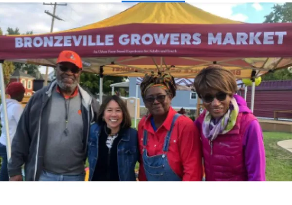 People posing in front of a Bronzeville Growers Market sign