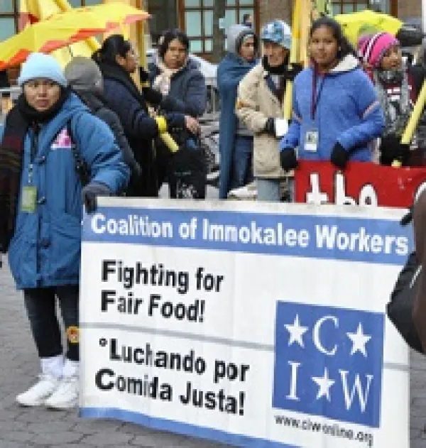 People outside in the cold and rain holding a Fighting for Fair Food sign