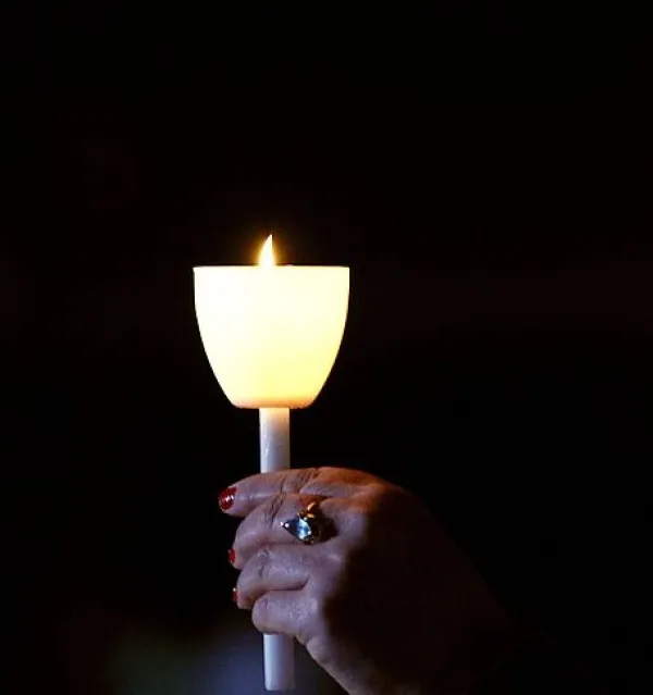A hand holding up a candle in the dark