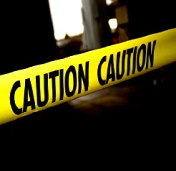 Bright yellow caution tape going across the picture with some dark images in the background