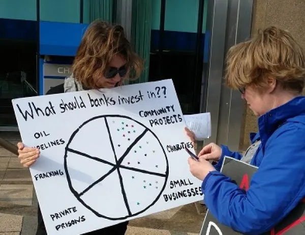 Girl holding sign about how Chase bank makes investments