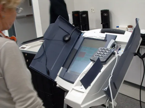 Older woman standing by an electronic voting machine