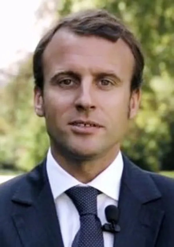 Young looking man with brown hair receding hairline against trees in background