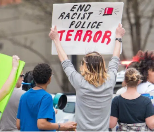 Woman holding sign saying End Racist Police Terror