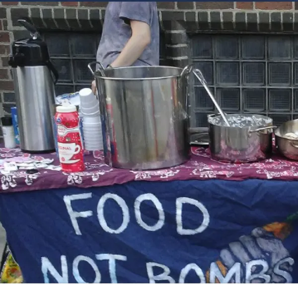 Table with pots and pans and banner saying Food Not Bombs