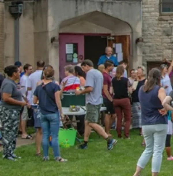 Lots of young people outside the door of a large stone church
