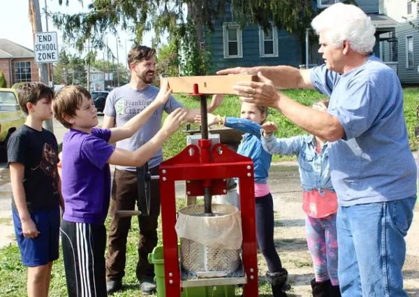 Two young white boys and two men working outside with some sort of garden device