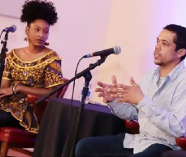 Two people on stage talking into mics