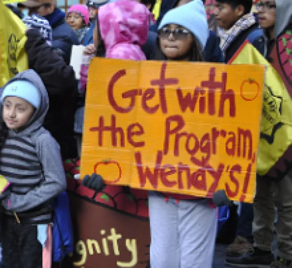 People standing outside and young girl holding a sign that says Get with the program, Wendy's