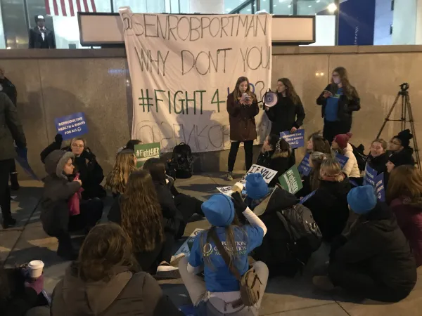 People protesting and sign saying Portman why don't you Fight4her