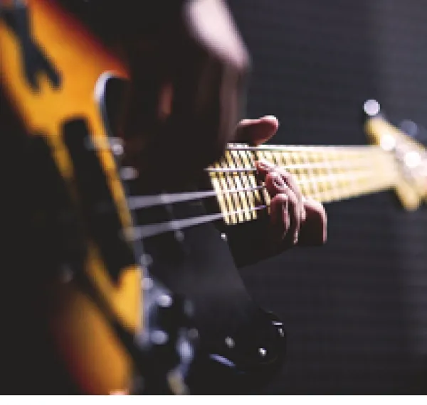 Sideways shot of a person playing a guitar close up of just the guitar and their hands