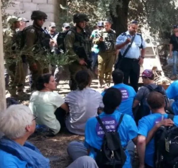 People sitting outside and men in military uniforms surrounding them