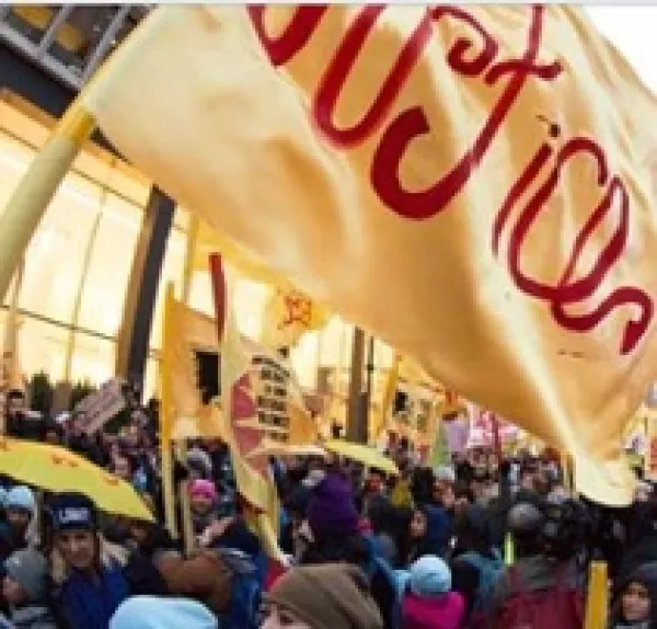 Yellow flag that says Justice in red and lots of people protesting outside