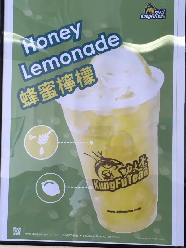 A sign with a cup with yellow liquid and words Kung Fu Tea