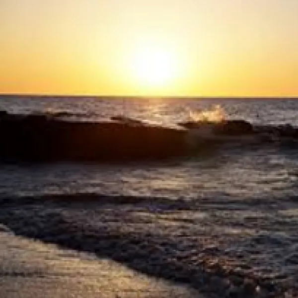 A beach with sun rising and waves coming in 