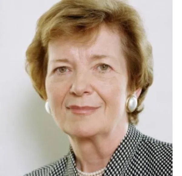 Middle aged white woman with earrings and a black and white suit