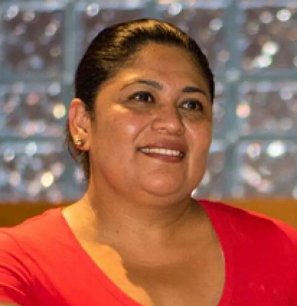 Latina woman with dark hair pulled back smiling in a red dress