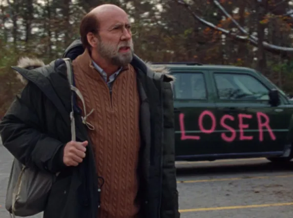 Man with backpack by a car with painting on it saying LOSER